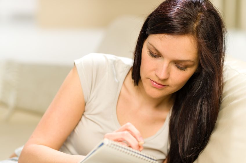 A woman pours her thoughts into her morning pages journal.